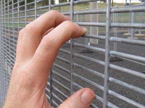 A hand is climbing the 356 high security fence.