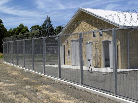 A house is surrounded by 358 high security fence with razor wire.
