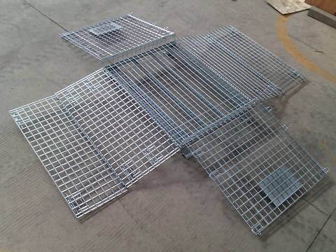 A silver wire mesh container with full dro gates open on ground.