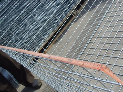 A half installed gabion mesh with its width being measured.