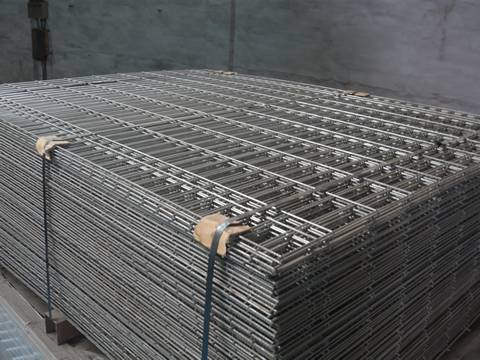 A stack of reinforcing mesh is packed with metal belt in workshop.