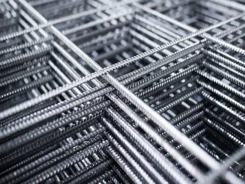 Many sheets of galvanized reinforcing mesh with square holes.