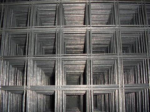 Many sheets of indented reinforcing mesh with square holes.