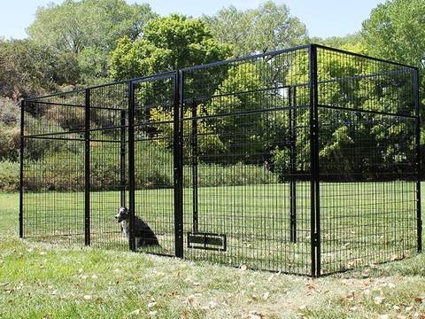 A huge welded wire dog kennel is in pasture with a dog in it.