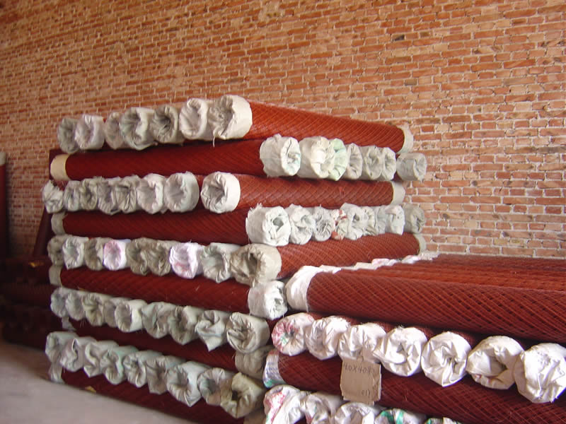 Many rolls of expanded metal mesh are packed with white woven bag on top.