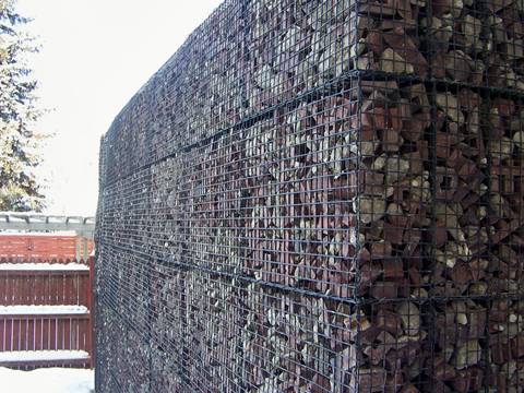 A heavy duty welded mesh gabion box with uniform mesh openings is full of rocks.