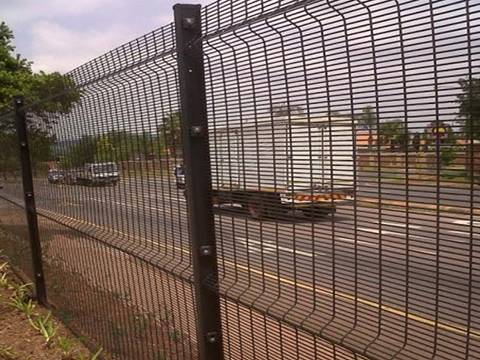 Many cars are passing through the road that has 358 high security fence.
