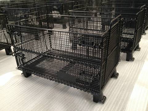 Many pieces of black welded wire container with supporting brackets in workshop.