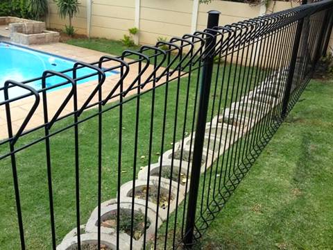 The black BRC fence is installed behind swimming pool.