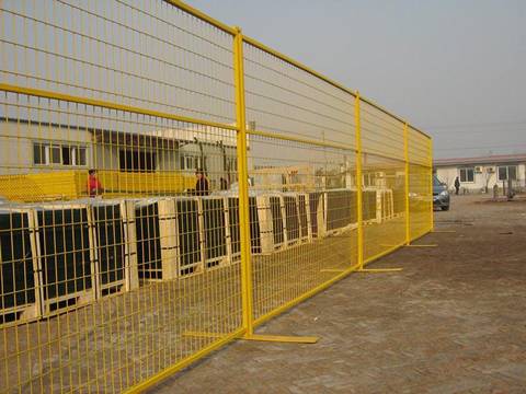 Two people are stand in the yard with yellow Canada portable fence.