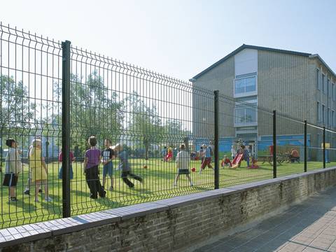 Curvy fence panels are used as fence in the playground, and many children are playing in it.