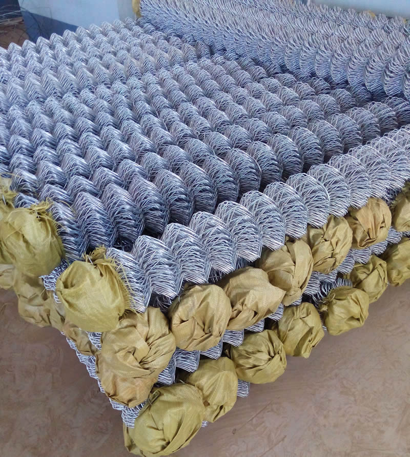 Many rolls of electric chain link fence with yellow woven bag on top.