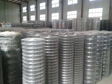 Many rolls of hot dipped galvanized welded wire mesh packaged with plastic film are in the warehouse.