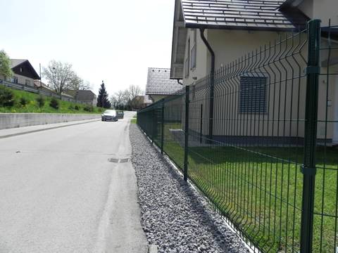 Beside the road, there is a PVC coated green welded wire mesh fence.
