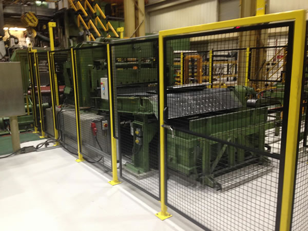 Black machine guards and orange posts are used as fencing in an factory.