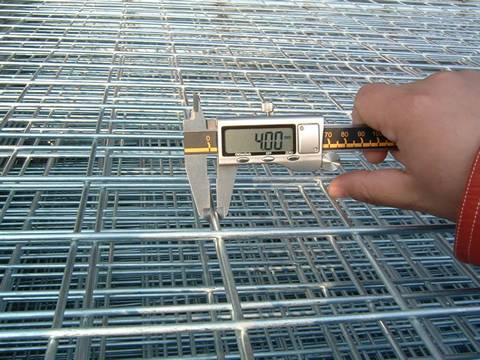 A people is measuring the wire diameter of welded wire mesh with ruler.