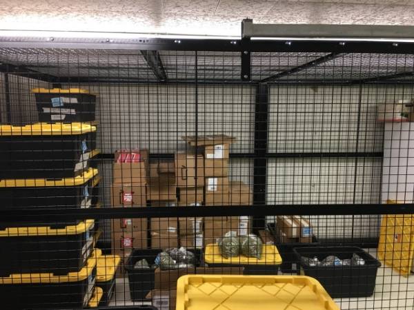 Several boxes and goods are stored in the wire mesh storage locker.